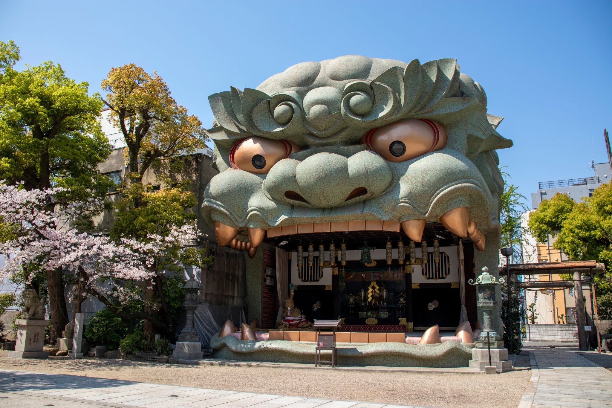 Namba Yasaka Shrine in Osaka, featuring its giant lion-head stage surrounded by cherry blossoms.