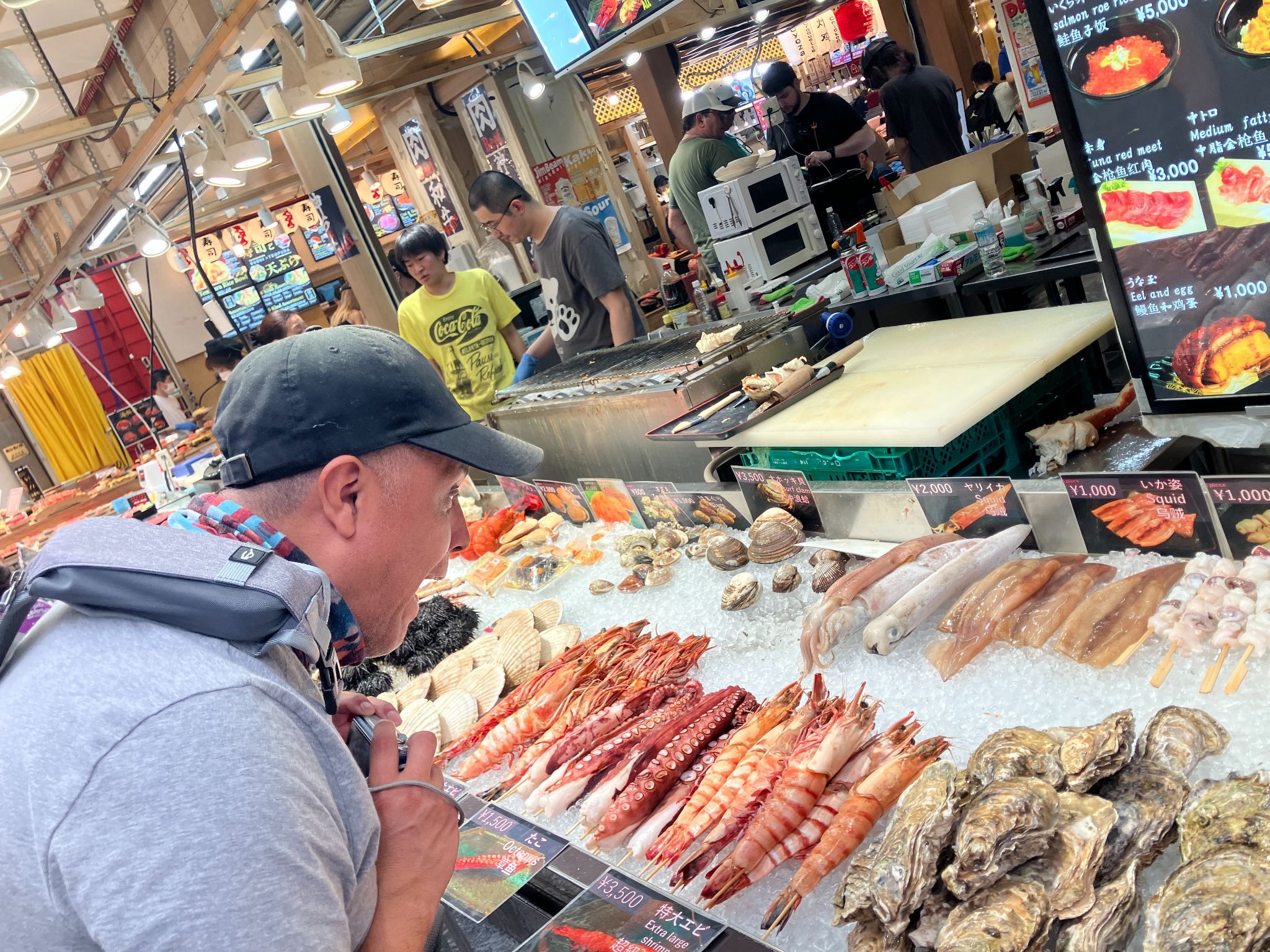 Kuromon Market in Osaka, with seafood stalls, local food vendors, and shoppers inside the covered market arcade.
